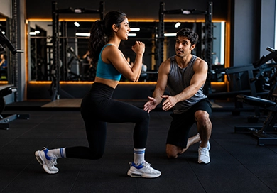 Personal trainer correcting form with client